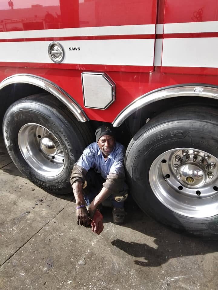 Ryan crouched between wheels of a fire truck during a detailing service